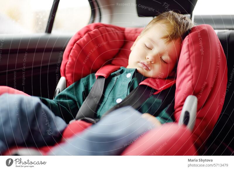Süßes Kleinkind Junge schläft in Autositz. Porträt eines hübschen kleinen Kindes während eines Familienausflugs. Sicherheit Transport von Baby mit dem Auto PKW