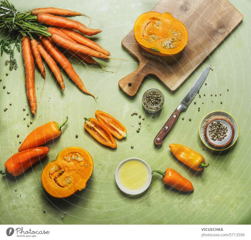 Orange Farbe Gemüse Kochen Vorbereitung auf grünen Tisch mit Schneidebrett und Küchenutensilien, Draufsicht. Gesundes und sauberes Essen orange Farbe