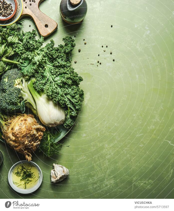 Lebensmittel Hintergrund mit grünem Gemüse Zutaten auf dem Küchentisch mit Schneidebrett und Speiseöl, Blick von oben. Gesundes, sauberes und entgiftetes Essen