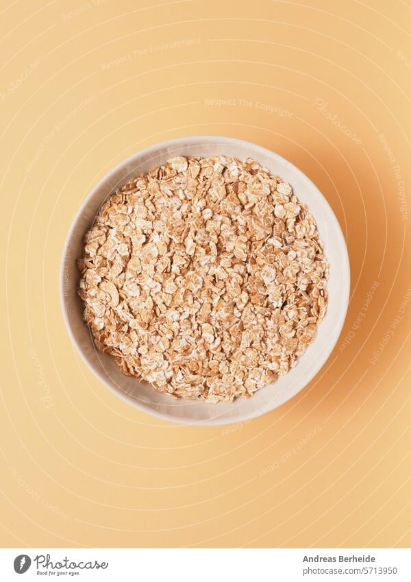 Bio Vollkorn Dinkelflocken in einer Schale auf einem sandfarbenen Fotokarton Lebensmittel Rohkost Reformkost vegan Frühstück glutenfrei Ernährung Gesundheit