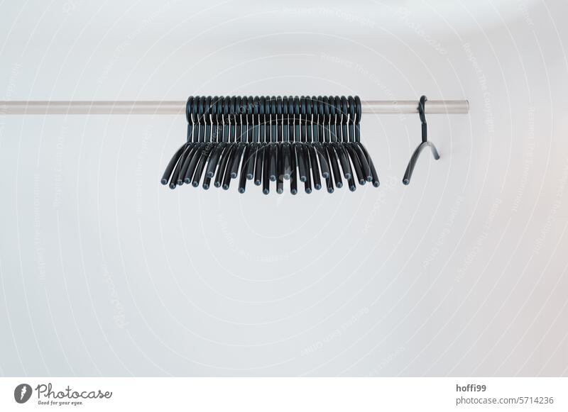 minimalistische Ansicht von Kleiderbügeln auf einer Stange vor hellem Hintergrund Gardrobe Kleiderständer hängen leer Leerstand Bekleidung Mode Kleidung Ordnung