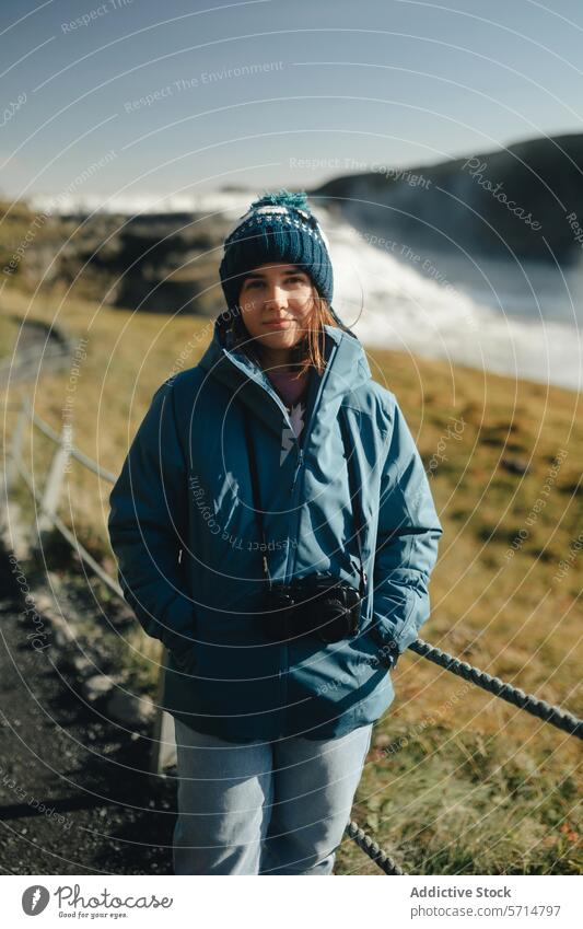 Touristin am Gullfoss-Wasserfall im sonnigen Island Frau Reisender blaue Jacke Strickmütze Lächeln Landschaft Natur im Freien reisen kalte Witterung
