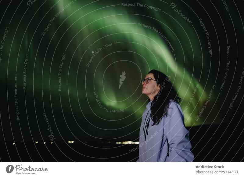 Frau bestaunt Nordlichter in Island Ehrfurcht Wunder Nacht Himmel grün glühen Natur astronomisches Phänomen reisen Abenteuer kalt Dunkelheit Stern beobachtend