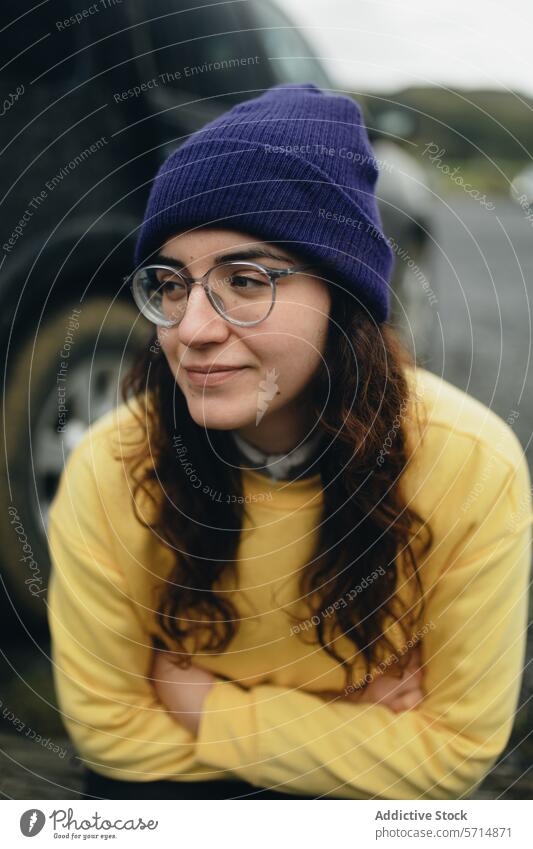 Lässige Frau mit lila Mütze beim Ausruhen im Freien Beanie Brille gelb Pullover krause Haare nachdenklich aussruhen Jugend Mode lässig purpur Accessoire Stil