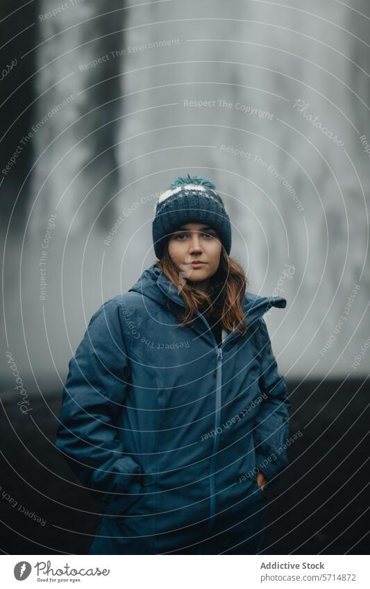 Junge Frau in blauer Jacke vor nebligem Wasserfall-Hintergrund Island reisen Natur Nebel Gelassenheit blaue Jacke Beanie beschaulich im Freien Abenteuer