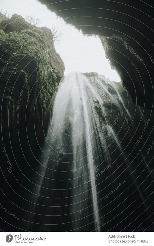 Majestätischer Wasserfall, der von felsigen Klippen in Island herabstürzt Kaskade Natur reisen Moos fließen strömen Sonnenlicht weiches Licht Nebel Spray
