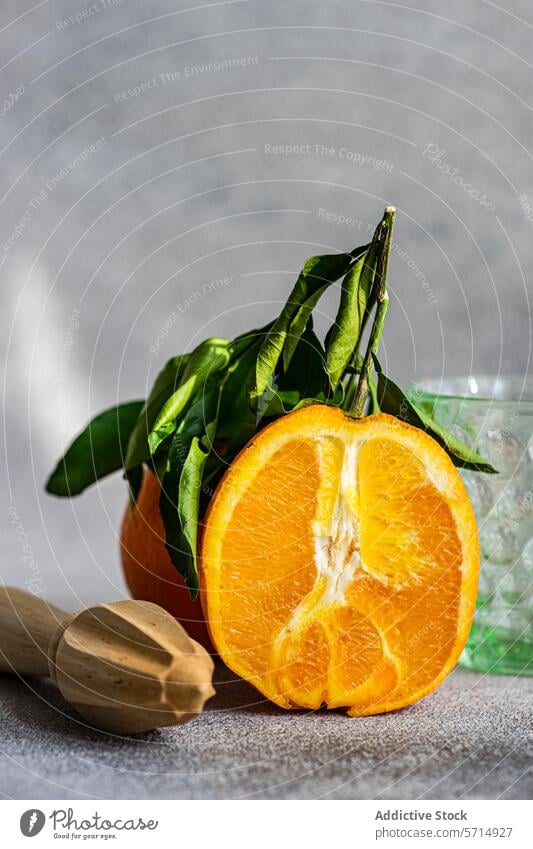 Frisch geschnittene Orange mit Blättern und hölzerner Saftpresse orange Frucht frisch Blatt Entsafter Zitrusfrüchte Gesundheit Lebensmittel pulsierend grün