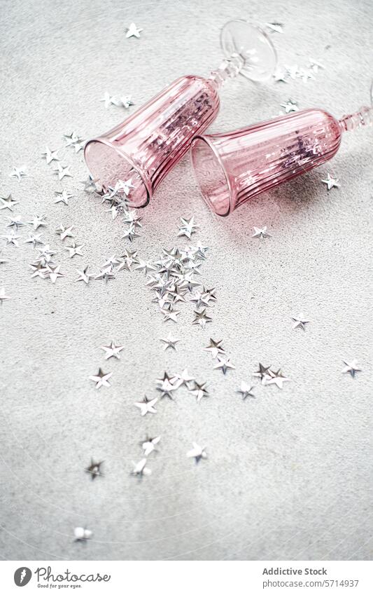 Rosa Champagnergläser und silberne Sterne auf grauem Hintergrund rosa Glas Silber Textur Feier leer liegen gestreut Oberfläche festlich Party Nachwirkungen