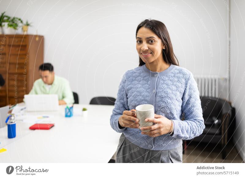 Lächelnde Geschäftsfrau mit Kaffeetasse im Büro Frau Tasse Kollege professionell heiter korporativ Arbeit Umwelt Schreibtisch Laptop männlich Hintergrund Pause