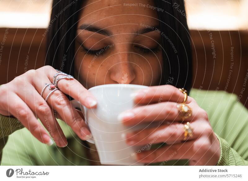 Junge Frau genießt ein heißes Getränk in einem Haus Kaffee Tasse schlürfen itim im Innenbereich gemütlich Heißgetränk junger Erwachsener dunkles Haar Ringe