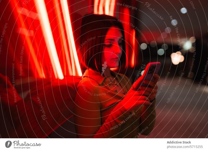 Urbaner Abend mit einer Frau, die ihr Smartphone im roten Neonlicht benutzt neonfarbig Licht urban Madrid vier Türme Geschäftsfeld modern Lifestyle jung