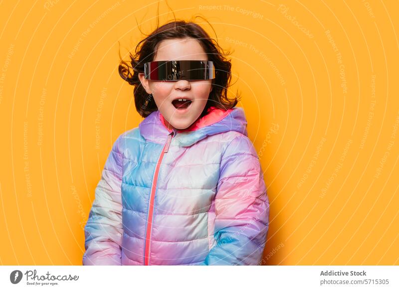 Überraschtes Mädchen mit offenem Mund, das eine reflektierende futuristische Brille und eine pastellfarbene Jacke vor einem orangefarbenen Hintergrund trägt