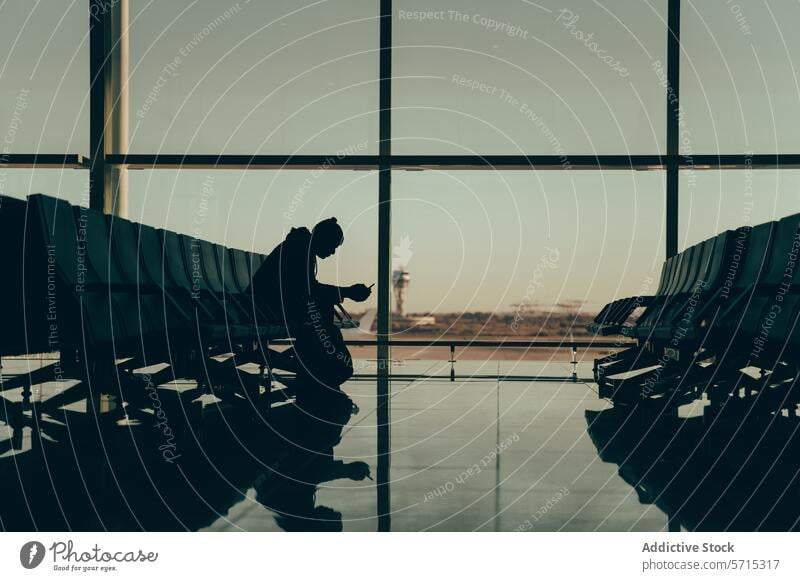 Silhouette einer anonymen Person, die auf einen Reisenden im Flughafenterminal wartet Mann Reisender Warten Terminal Sitzen Telefon Kontrollturm allein Stuhl
