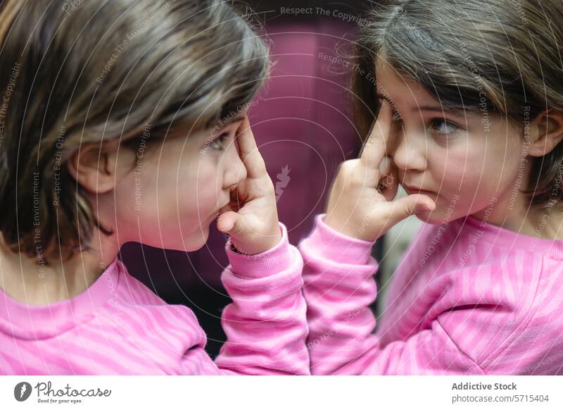 Mädchen, das sich in einem Spiegel reflektiert und Rosa trägt Reflexion & Spiegelung rosa Top Kind Neugier Unschuld Kontemplation nachdenklich im Innenbereich