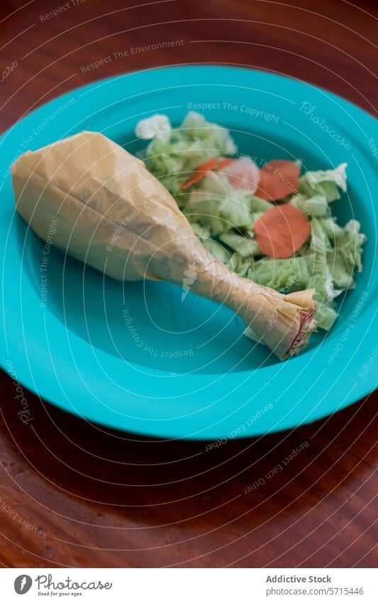 Konzeptuelles Plastikessen auf dem Teller eines Kindes Kunststoff Lebensmittel Fälschung Hähnchen Trommelschlegel Papier Salatbeilage blau Kinderteller