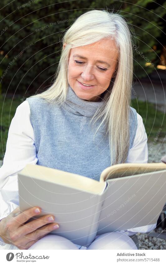 Gelassene Frau in den 50ern, vertieft in die Lektüre eines Buches, ein Beispiel für einen entspannten Lebensstil 50s lesen friedlich Freizeit Lifestyle reif