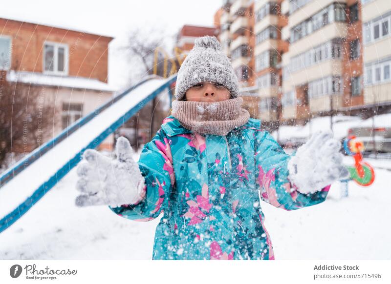 Ein Kind in einer bunten Jacke spielt mit Schnee auf einem Spielplatz im Winter spielen bunte Jacke im Freien Schneeflocke Aktivität kalt Spaß Genuss
