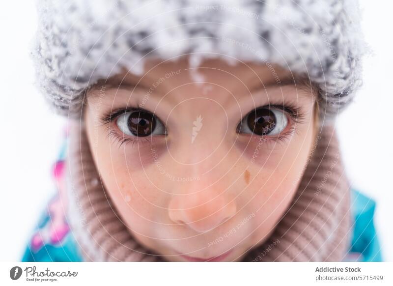 Nahaufnahme der Augen eines Kindes, das eine Wollmütze in einer verschneiten Umgebung trägt Starrer Blick Winter im Freien Neugier Unschuld Gesicht Wärme