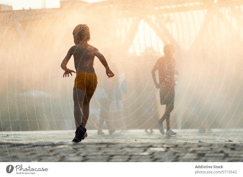 Die anonyme Silhouette eines Kindes läuft durch den Nebel eines Stadtbrunnens, während die Sonne untergeht und einen warmen, goldenen Schein auf die Stadtlandschaft wirft