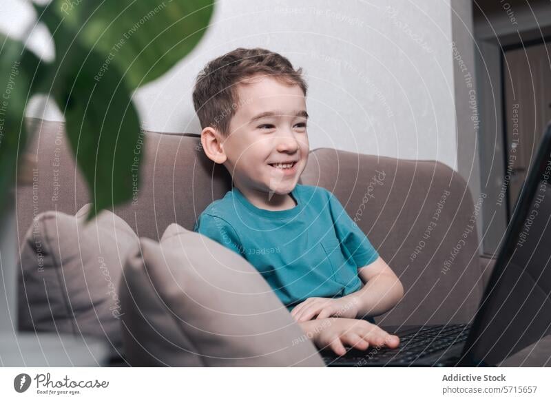 Ein Kind lächelt, während es sich mit moderner Technologie beschäftigt Technik & Technologie Laptop Lächeln heimwärts Interaktion Junge Computer digital Lernen