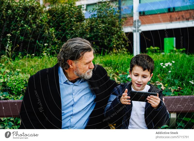 Großvater und Enkel genießen die Technik auf einer Parkbank Smartphone Bank Familie Technik & Technologie Bonden Generation älter Kind Junge Mann Interaktion