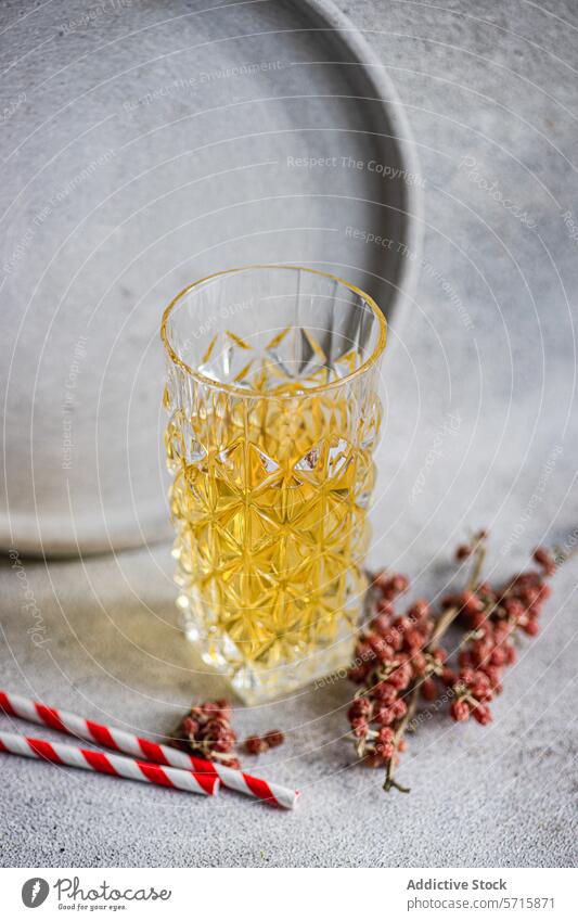 Elegant strukturiertes, mit Apfelwein gefülltes Glas mit roten Beeren und einem gestreiften Strohhalm vor einem Betonhintergrund texturiert Hintergrund trinken
