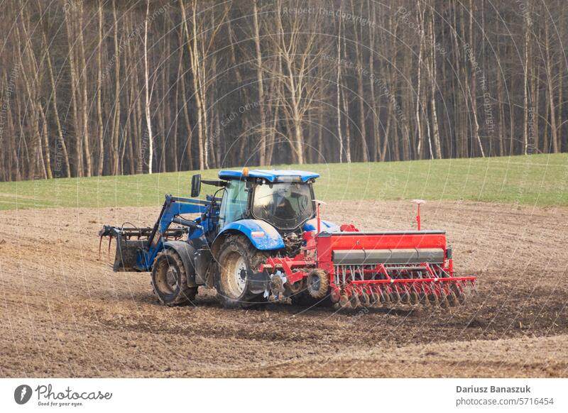 Landwirtschaftlicher Traktor mit Sämaschine auf dem Feld, Frühlingstag Samen Ackerbau Maschine landwirtschaftlich Aussaat Bauernhof Industrie Arbeit Gerät
