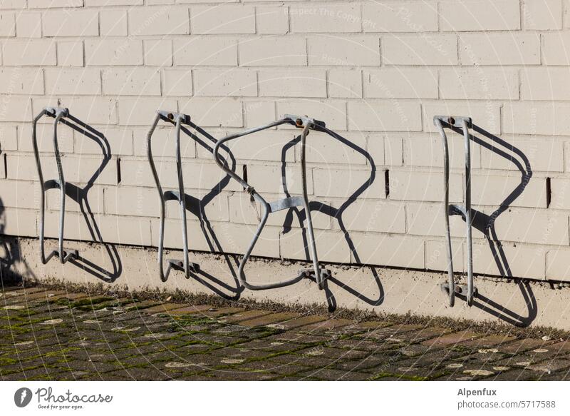 vier Ständer Fahrradständer abstellen Fahrradparkplatz Menschenleer Metall verbogen verbogenes kaputt parken Farbfoto Schatten Schattenspiel Abstellplatz