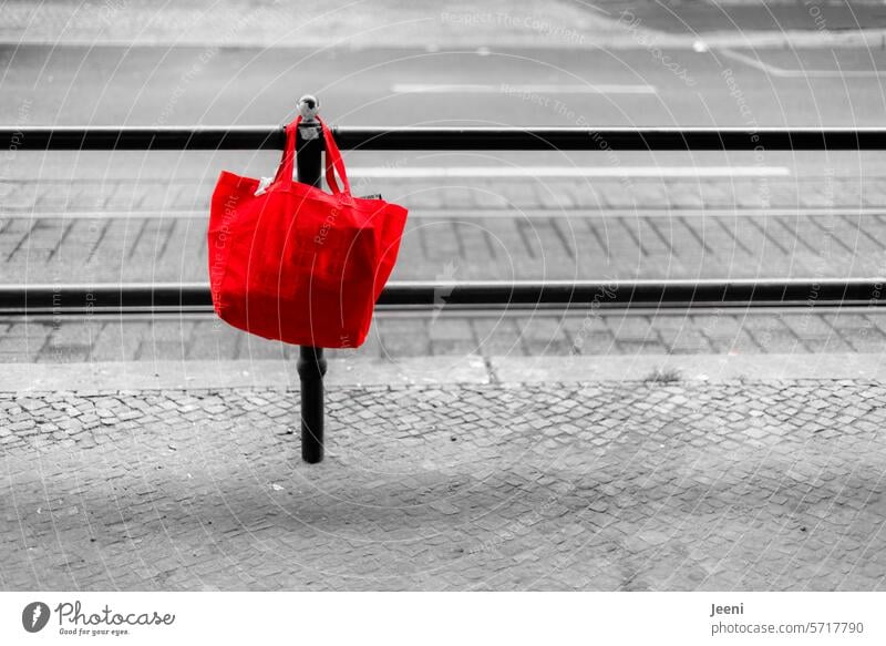 Rote Tasche am Straßenrand rot Beutel hängen vergessen Abgrenzung Zaun Wege & Pfade Barriere Grenze Verkehrswege Stadt Kopfsteinpflaster Bürgersteig Linie