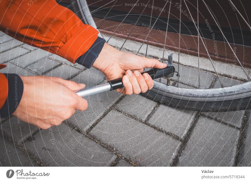 Ein Mann bereitet sein Rennrad auf die Saison vor. Er bläst den Fahrradschlauch mit einer Handpumpe auf. Sport im Freien. Regelmäßige Wartung Pumpe Dienst Rad