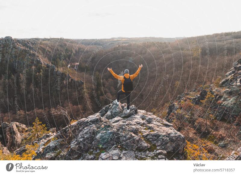 Ein Reisender in einer gelben Jacke steht am Rande eines Felsens und genießt einen Moment der Entspannung mit Blick auf das Divoke sarky Tal, Prag, Tschechische Republik. Erfolgreich sein