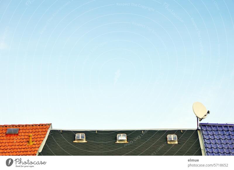 drei unterschiedlich gedeckte Dächer mit Dachfenstern und einer Satellitenschüssel vor hellblauem Himmel Hausdach Dachziegel Ziegeldach Bitumenschindeln