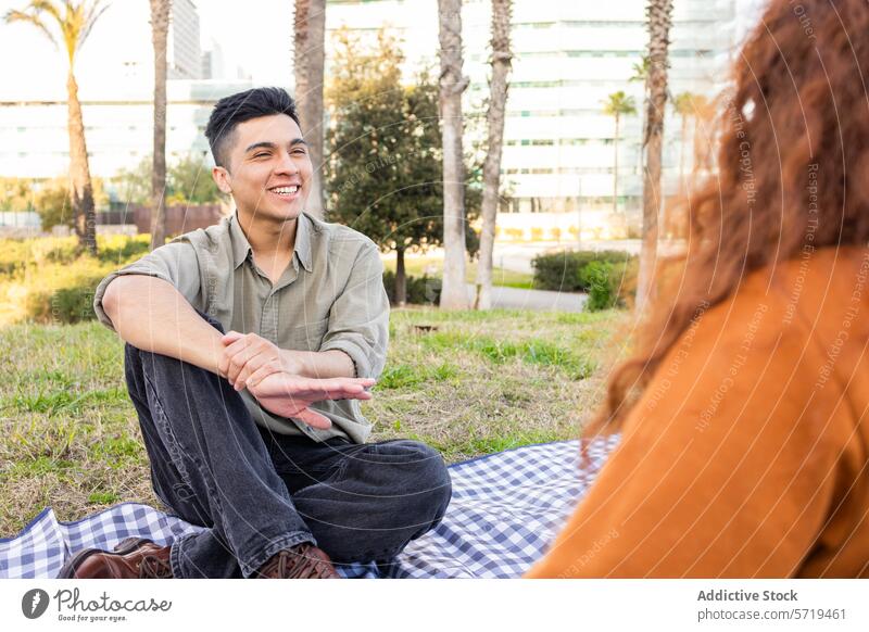 Studenten unterhalten sich bei einem sonnigen Picknick Schüler Park Gespräch Lächeln Mann Frau multiethnisch jung urban lässig im Freien Freizeit Freundschaft
