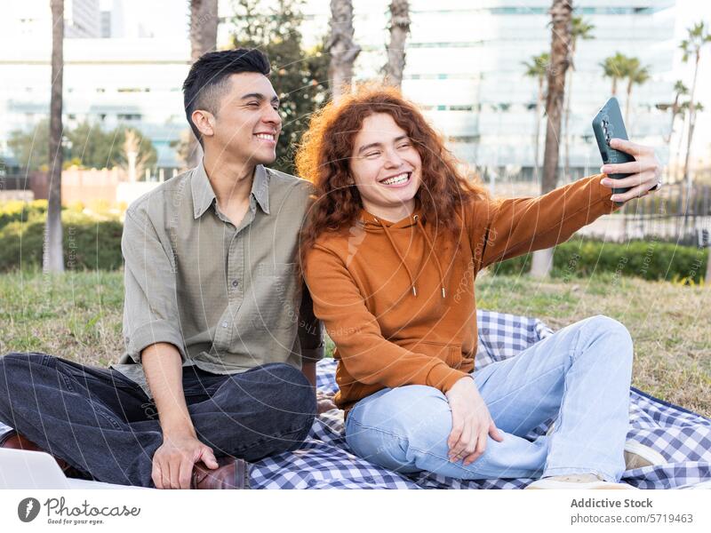 Lächelnde Studenten, die ein Picknick genießen und ein Selfie machen Schüler Smartphone Glück Frau Mann Latein Rotschopf Park Jugend Vielfalt im Freien lässig