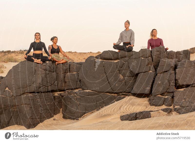 Yoga-Praktizierende meditieren auf Strandfelsen Meditation Lotus-Pose padmasana Achtsamkeit Klasse Steine robust schemenhaft Frauen Praktiker im Freien