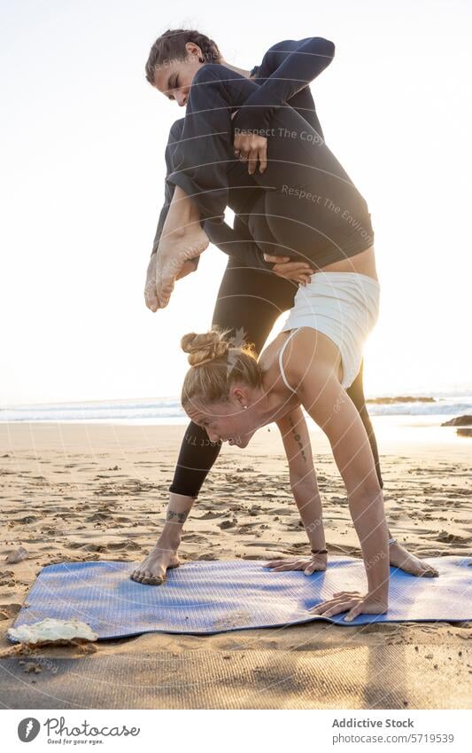 Yoga Duo übt Posen am Strand bei Sonnenuntergang üben Vorwärtsbeuge Unterstützung Fitness Wellness Gesundheit Sand duo Partnerschaft Gleichgewicht Ruhe Frieden