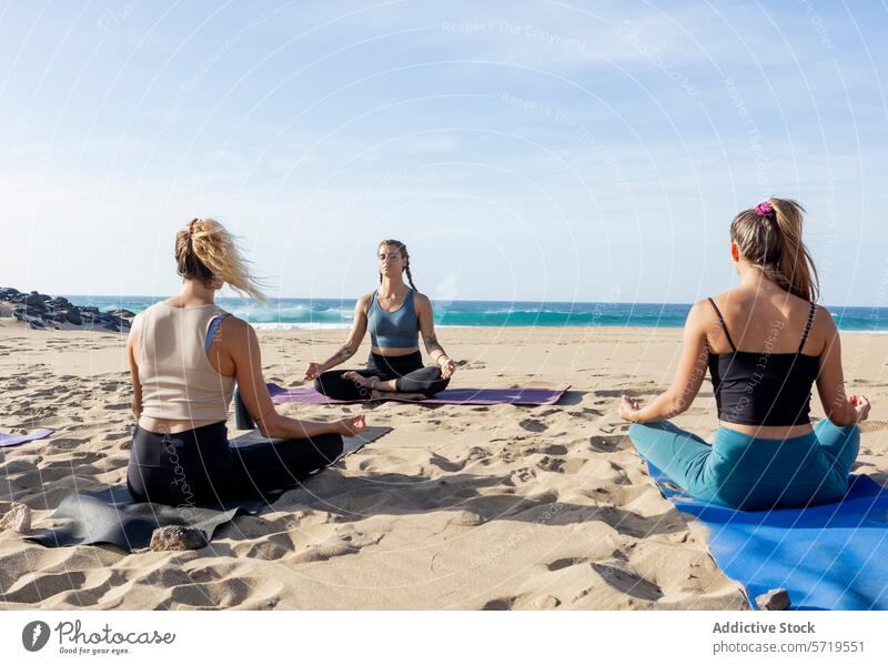 Yoga-Kurs bei Sonnenuntergang am Strand in friedlicher Meditationshaltung Pose sukhasana Klasse Ruhe Sand Meer Wellness Fitness Gesundheit Erholung Harmonie