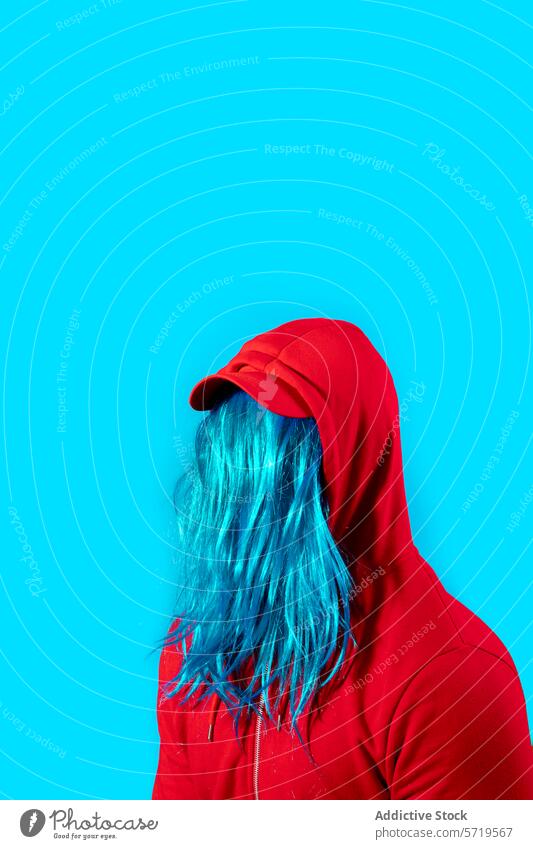 Mysteriöse Person mit blauen Haaren und rotem Kapuzenpulli auf blauem Hintergrund Behaarung pulsierend farbenfroh Stil Mode Anonymität unkenntlich gesichtslos