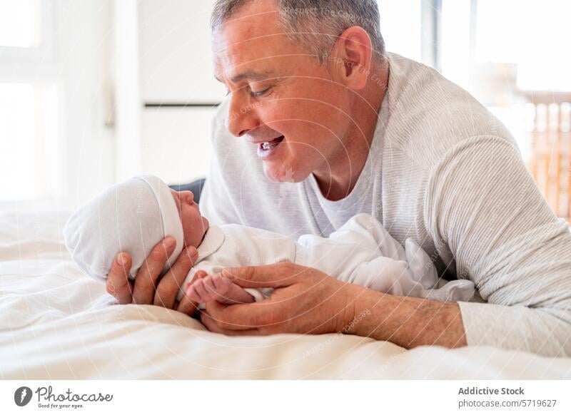 Ein liebenswerter Moment, in dem ein verspielter Vater mit seinem aufmerksamen neugeborenen Baby interagiert und beide eine herzliche Familienverbindung genießen