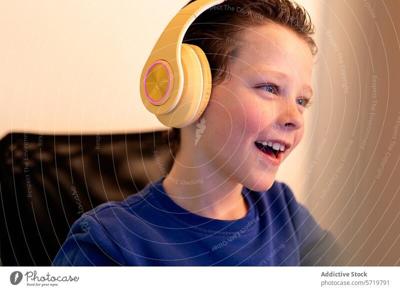 Ein begeisterter Junge mit Kopfhörern lacht, während er auf einen Computerbildschirm schaut, was auf eine positive Online-Interaktion oder -Entdeckung hindeutet