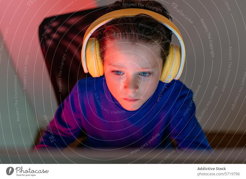 Intensiv konzentriertes Kind mit Kopfhörern am Computer, vertieft in ein Online-Lernprogramm oder -spiel Fokus Lernen online Bildung Technik & Technologie