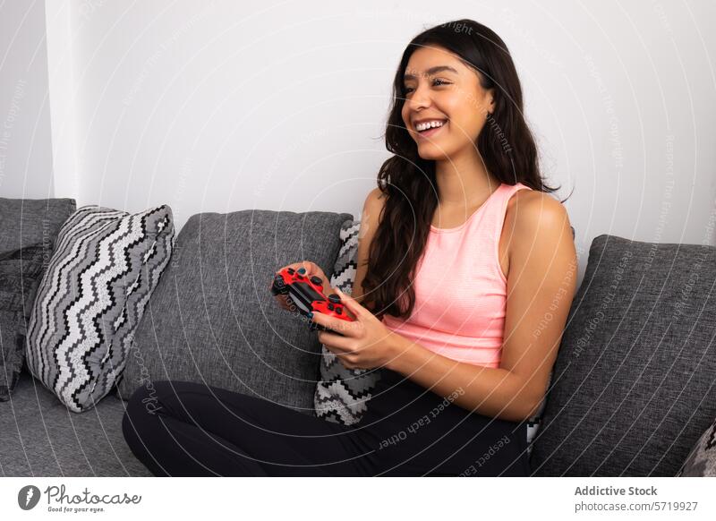 Lächelnde Frau genießt das Spielen auf der Couch Liege Game-Controller Drahtlos Erholung Entertainment Freude Freizeit im Innenbereich Wohnzimmer lässig