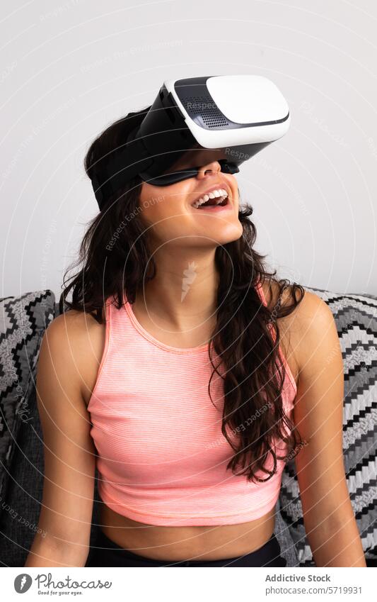 Lächelnde junge Frau, die virtuelle Realität erlebt Erwachsener Virtuelle Realität vr-kopfhörer hispanisch nahöstlich 20s Vergnügen Freude rosa Oberteil