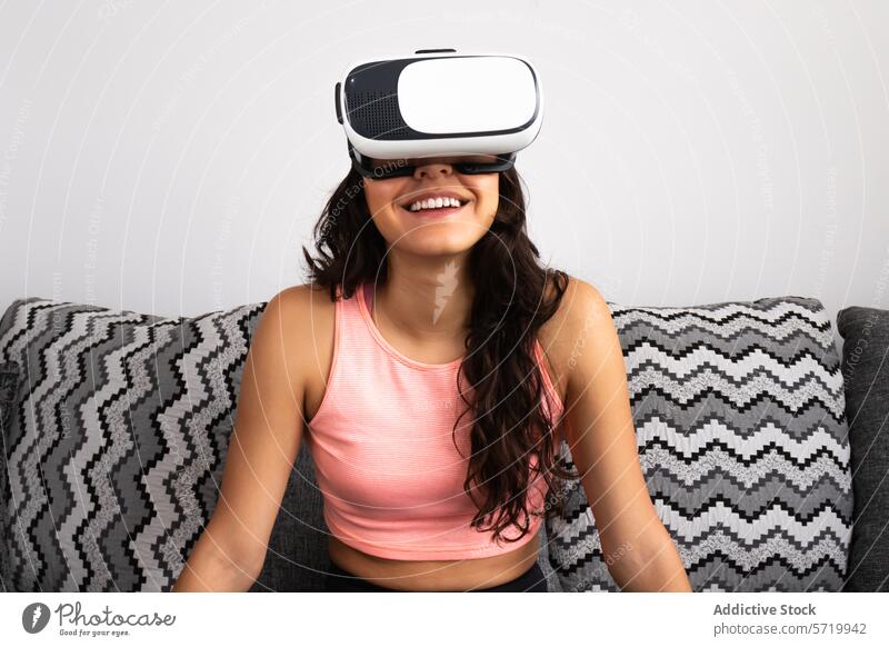 Lächelnde junge Frau, die virtuelle Realität erlebt Erwachsener Virtuelle Realität vr-kopfhörer hispanisch nahöstlich 20s Vergnügen Freude rosa Oberteil