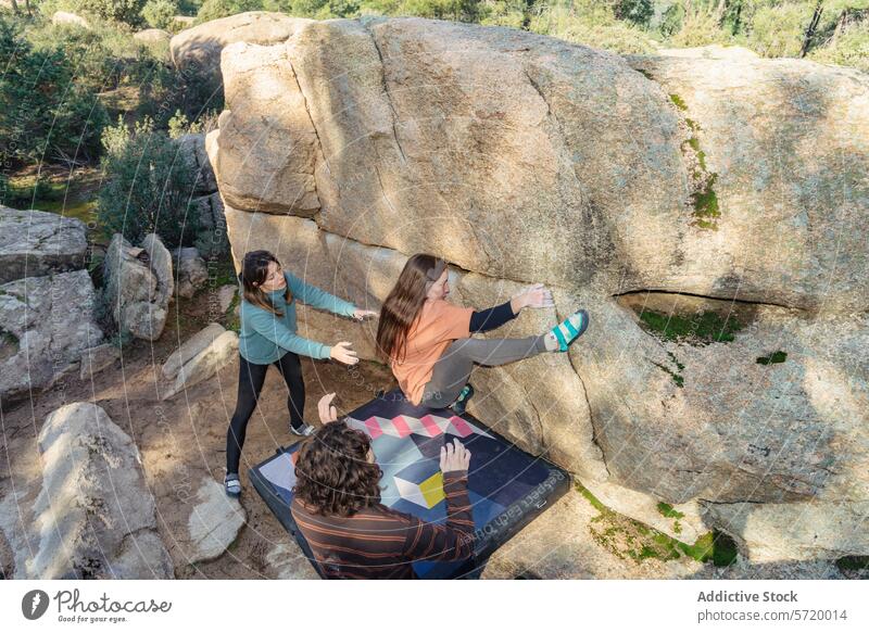 Von oben: Konzentrierte Kletterer arbeiten gemeinsam an einem Boulderproblem im Freien, wobei ein Spotter für ihre Sicherheit sorgt Bouldern Teamwork Aufklärer
