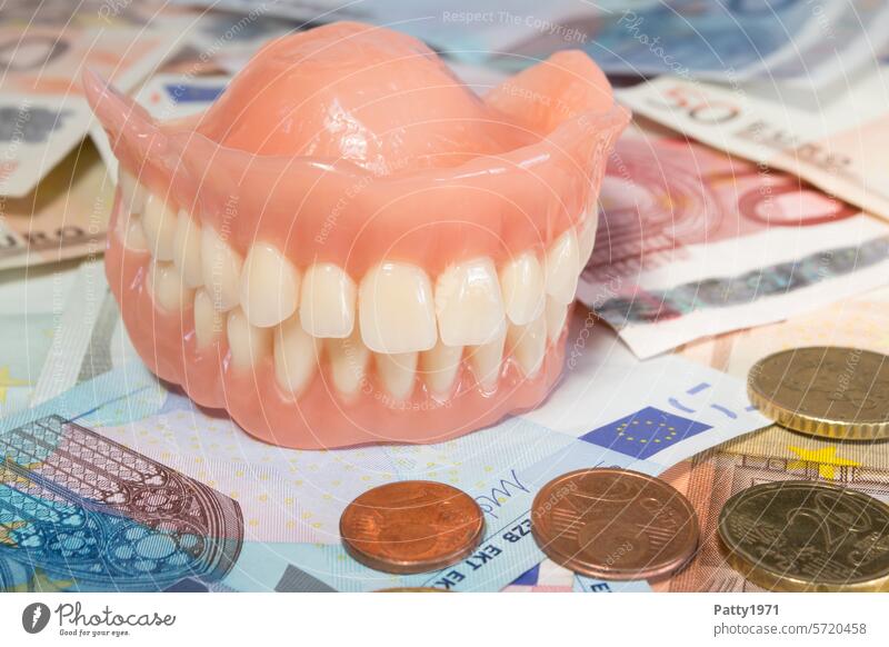 Künstliches Gebiss liegt auf vielen Geldscheinen. Zähne Gesundheit teuer Zuzahlung Gesundheitswesen Zahnmedizin Nahaufnahme Zahnarzt dental Eigenanteil