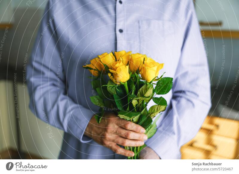 Ein Mann im blauen Hemd hält einen gelben Rosenstrauß in seinen Händen Blumenstrauß Geschenk halten Geburtstag Valentinstag Frühling Liebe Muttertag Blüte