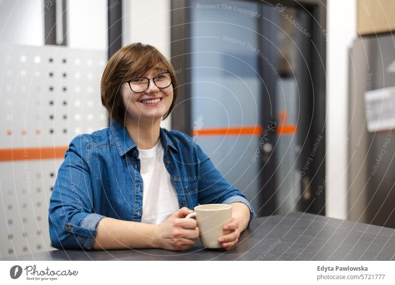 Junge Frau bei einer Kaffeepause in der Büroküche Lächeln positive Emotion Sitzen Küche trinken Tasse Kaffee Business Mitarbeiter Job Menschen Beruf arbeiten