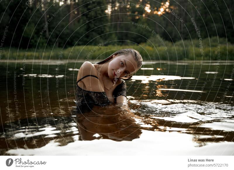 Wasser ist der beste Freund dieses wunderschönen brünetten Mädchens. Sie ist in einem Fluss in einer goldenen Stunde umgeben von der großen grünen Natur. Ihr Kleid ist nass und sie spielt makellos mit der Kamera.
