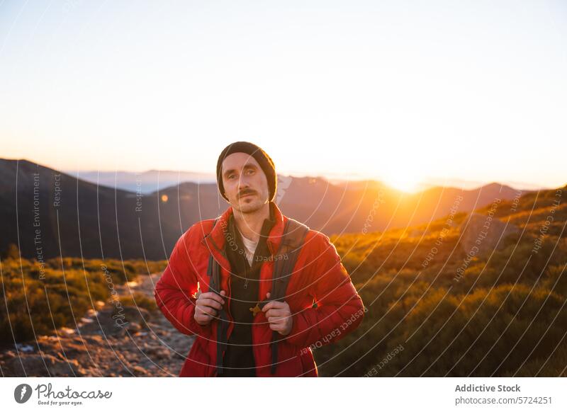 Wanderer genießt den Sonnenuntergang auf einem Bergpfad Berge u. Gebirge Nachlauf Gelassenheit warm glühen männlich rote Jacke Beanie im Freien Natur Abend